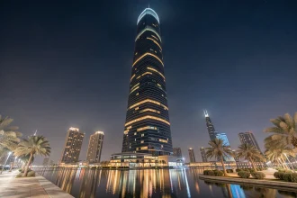 Tour Almas de nuit à Jumeirah Lake Towers avec reflets sur le lac et skyline de Dubaï en arrière-plan